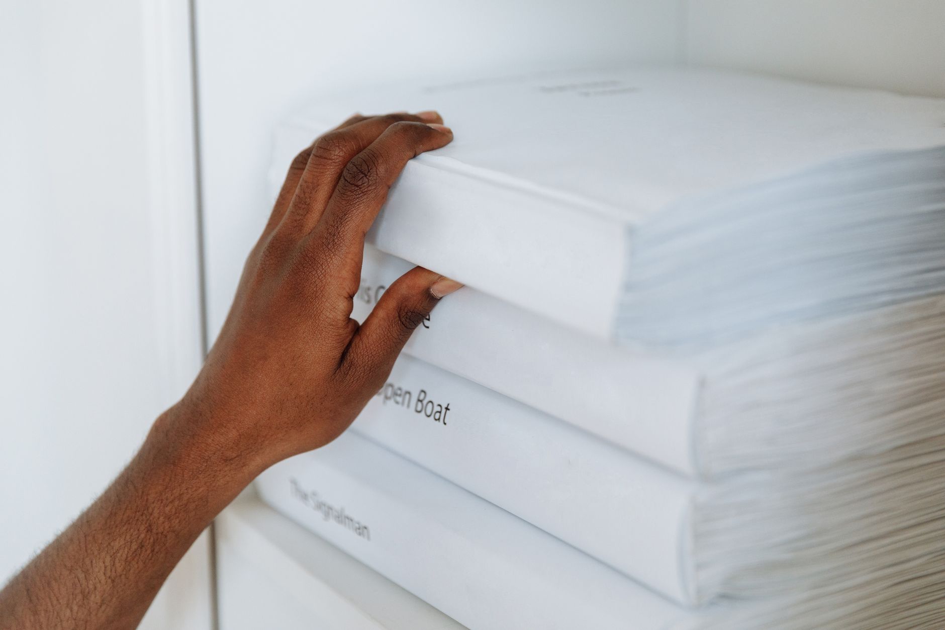 Close-up of a hand reaching for a script on a shelf, emphasizing detail and intention.