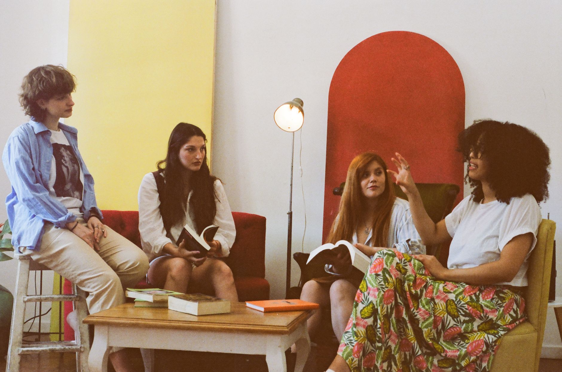 Four women discuss books while sitting together in a living room.
