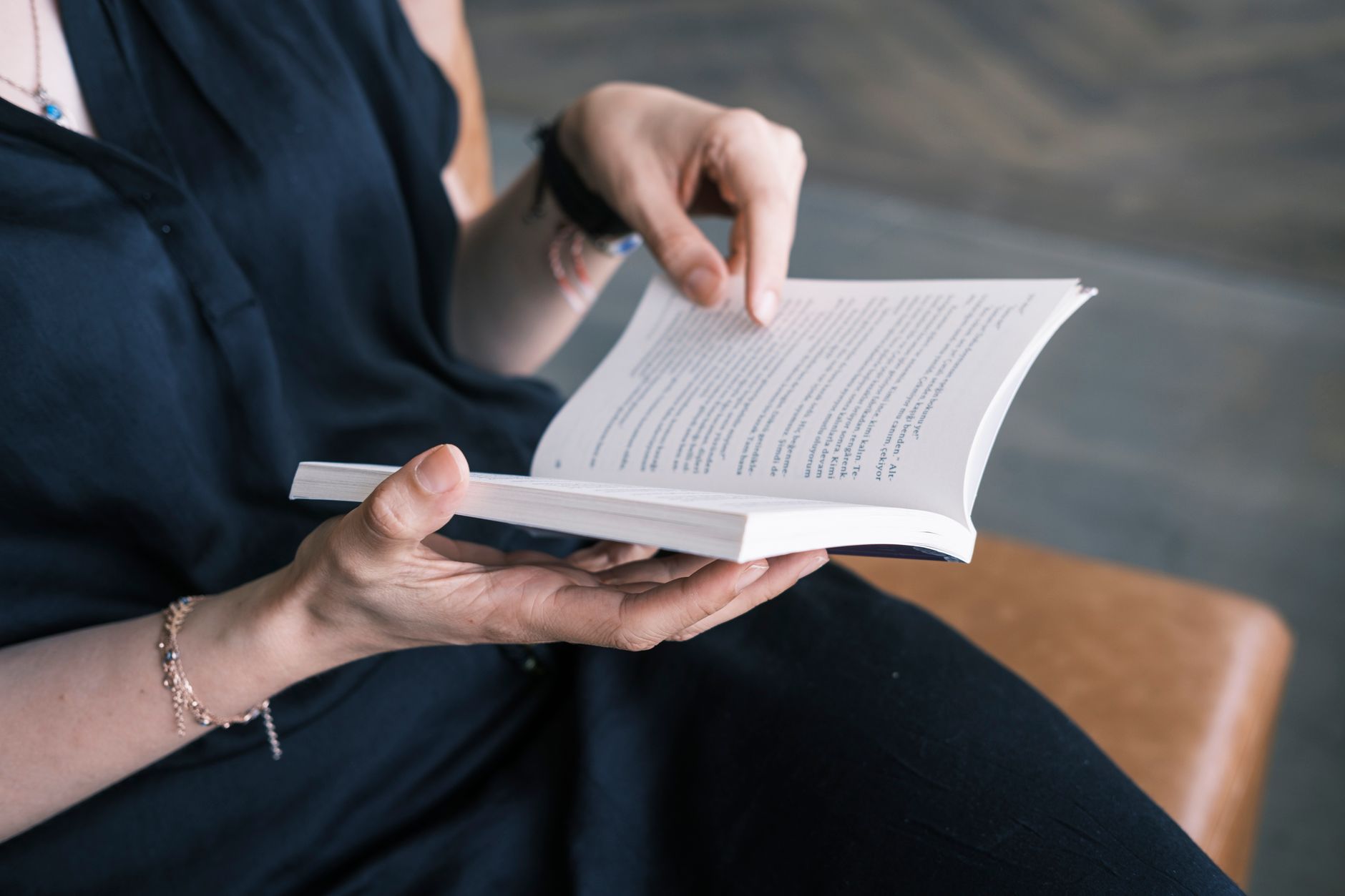 Person reading a small paperback book indoors.